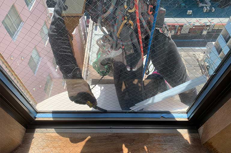 ロープアクセスによる窓ガラス交換作業の様子