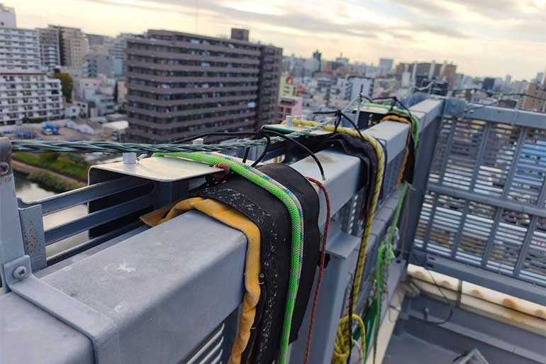 屋上フェンスの上部にローププロテクターを当て、複数のロープを掛けている様子